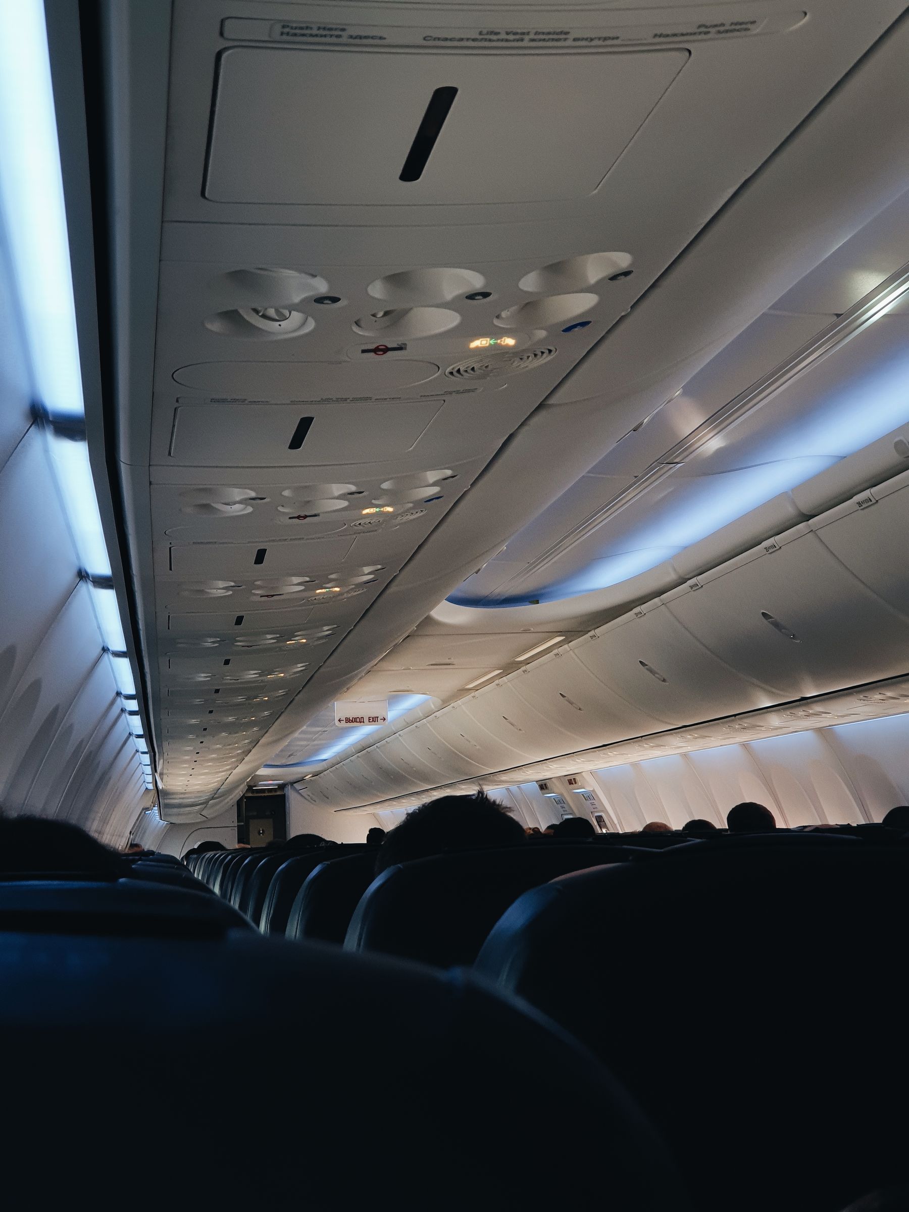 Cabin lights running along the closed overhead bins of a night flight