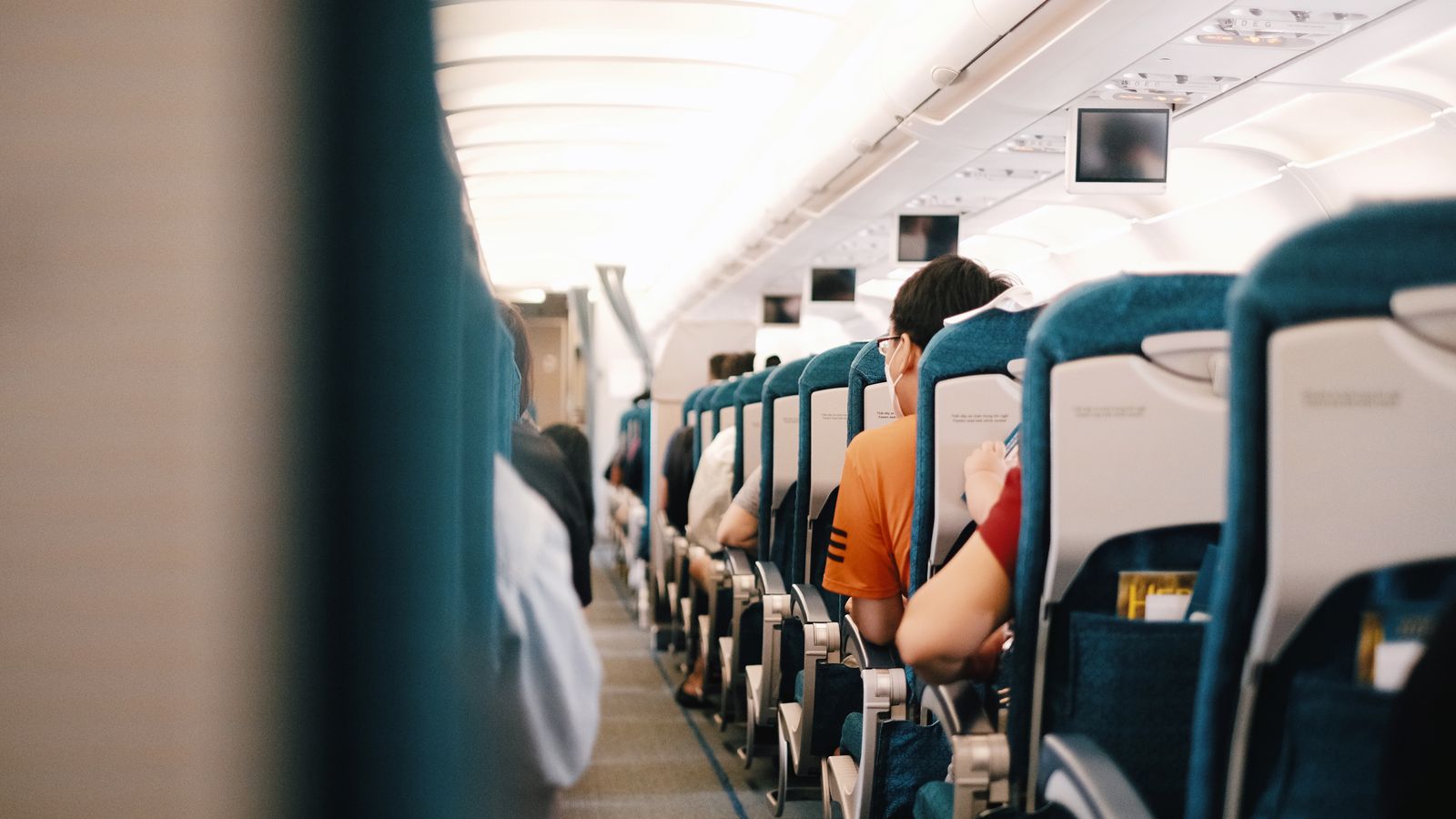 Looking forward down the aisle of a single-aisle cabin, seats to the right and closed bins overhead